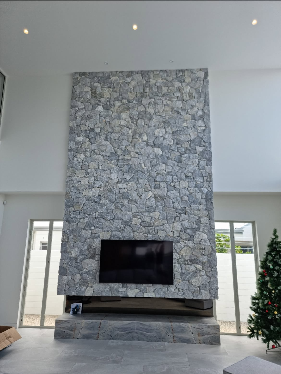 Grey dry-stack fireplace surround with a television above the hearth